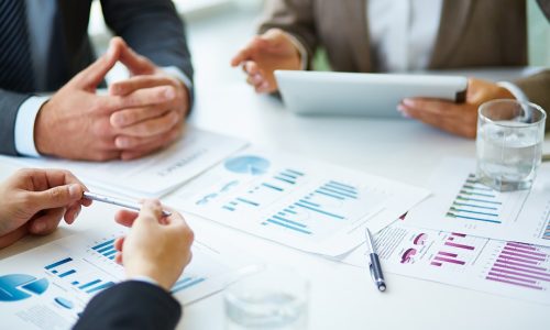 Image of business documents, pen and glasses on workplace during meeting of partners